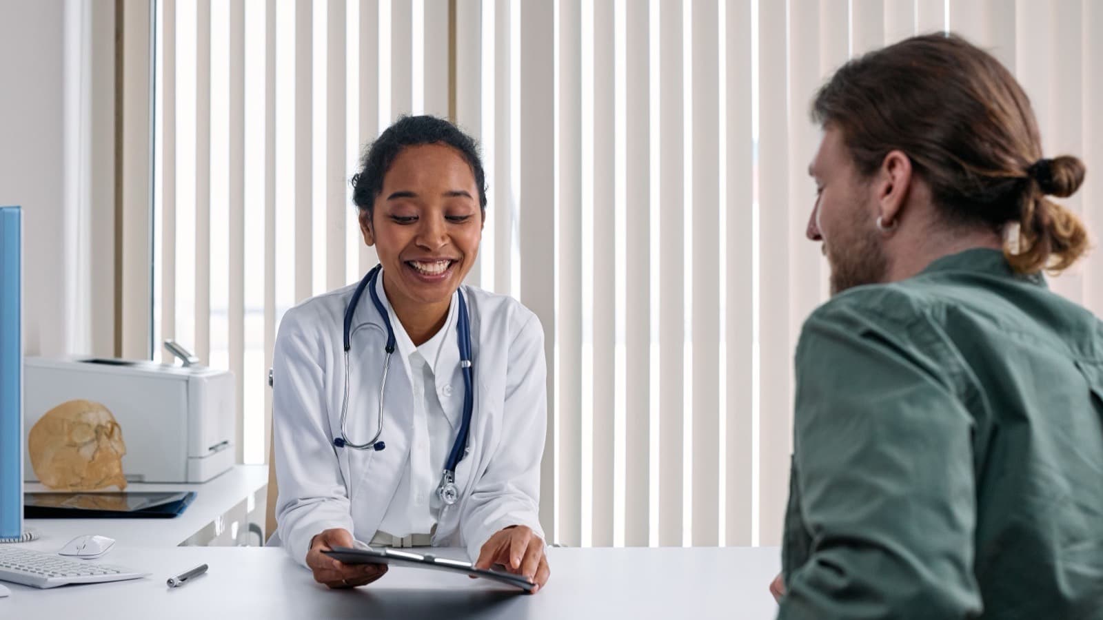 A doctor smiling while talking with a patient across a desk