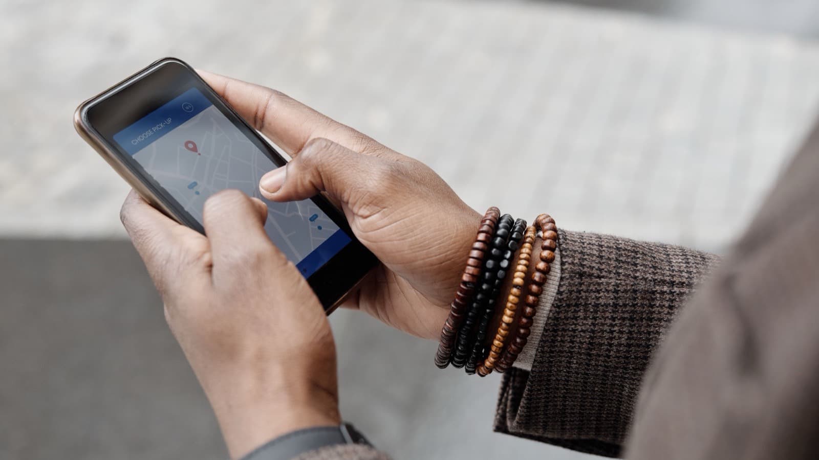Hands holding a phone with a map and a location pin on the screen
