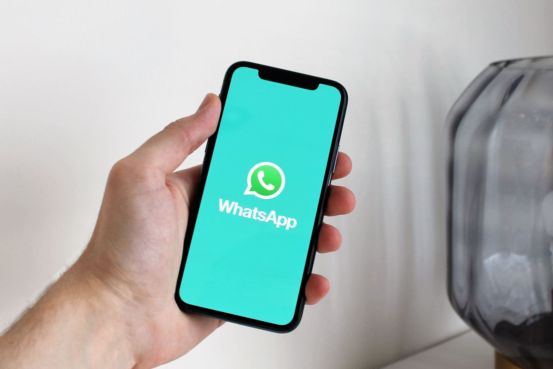 A hand holding a phone with WhatsApp open